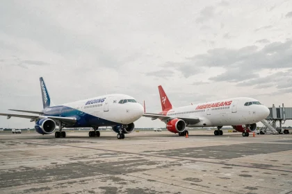 Deux avions commerciaux côte à côte sur le tarmac d'un aéroport, illustrant la rivalité entre Boeing et Airbus